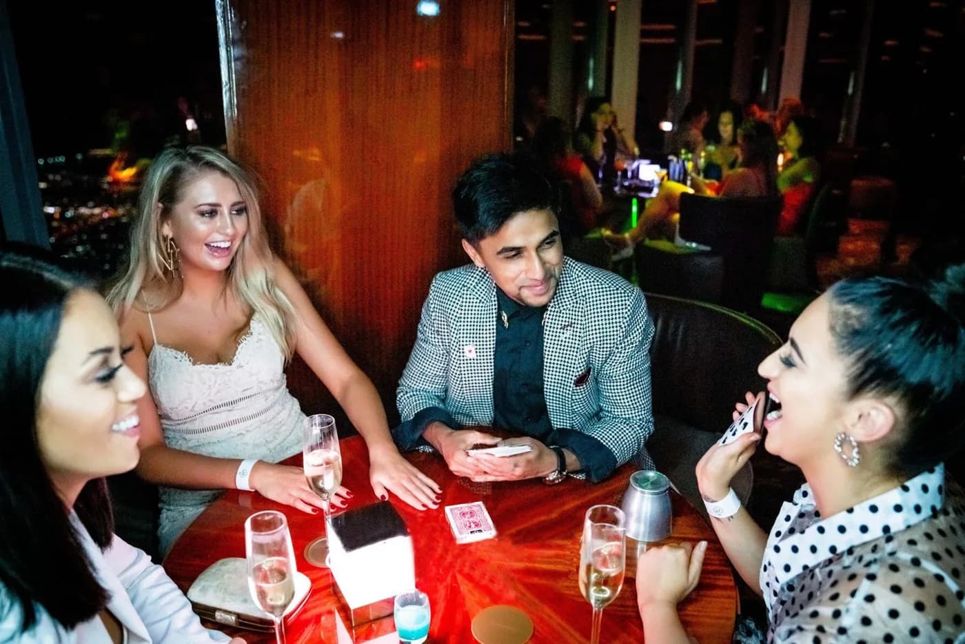 Nabeel performs card magic with guests seated at a restaurant table.